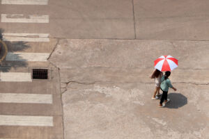 In the hot sun, there were still people walking on the road with umbrellas.