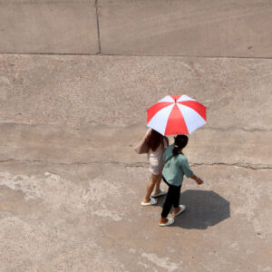 In the hot sun, there were still people walking on the road with umbrellas.