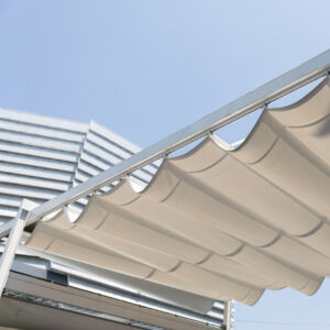 A white canopy with a blue sky in the background. The canopy is open and the sky is clear. Folded pergola with detail of fabric awning.