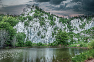 Close up of climbing rock Filipov kuk and lake with dramatic sunset. Velebit Nature Park, Croatia