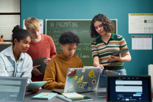 Group of multiethnic teenagers collaborating on laptop in classroom.