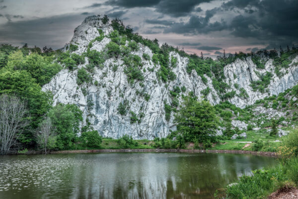 Close up of climbing rock Filipov kuk and lake with dramatic sunset. Velebit Nature Park, Croatia